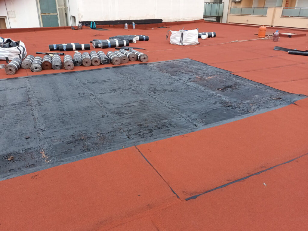 Cubierta plana de un edificio de viviendas durante una impermeabilización para comunidades de propietarios, con los rollos de lámina asfáltica preparados